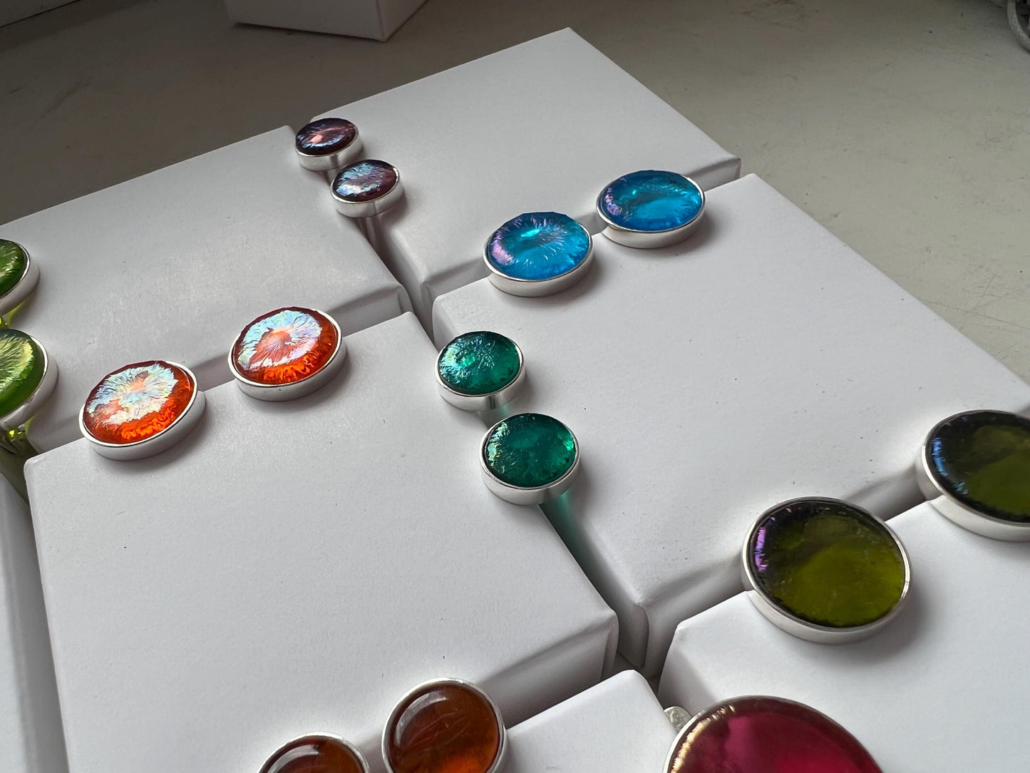 Colorful fused glass stud earrings displayed on white background.
