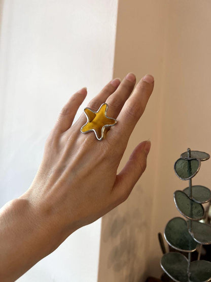 Handmade stained glass ring shaped like a starfish. Ocean-inspired statement jewelry in orange tones.