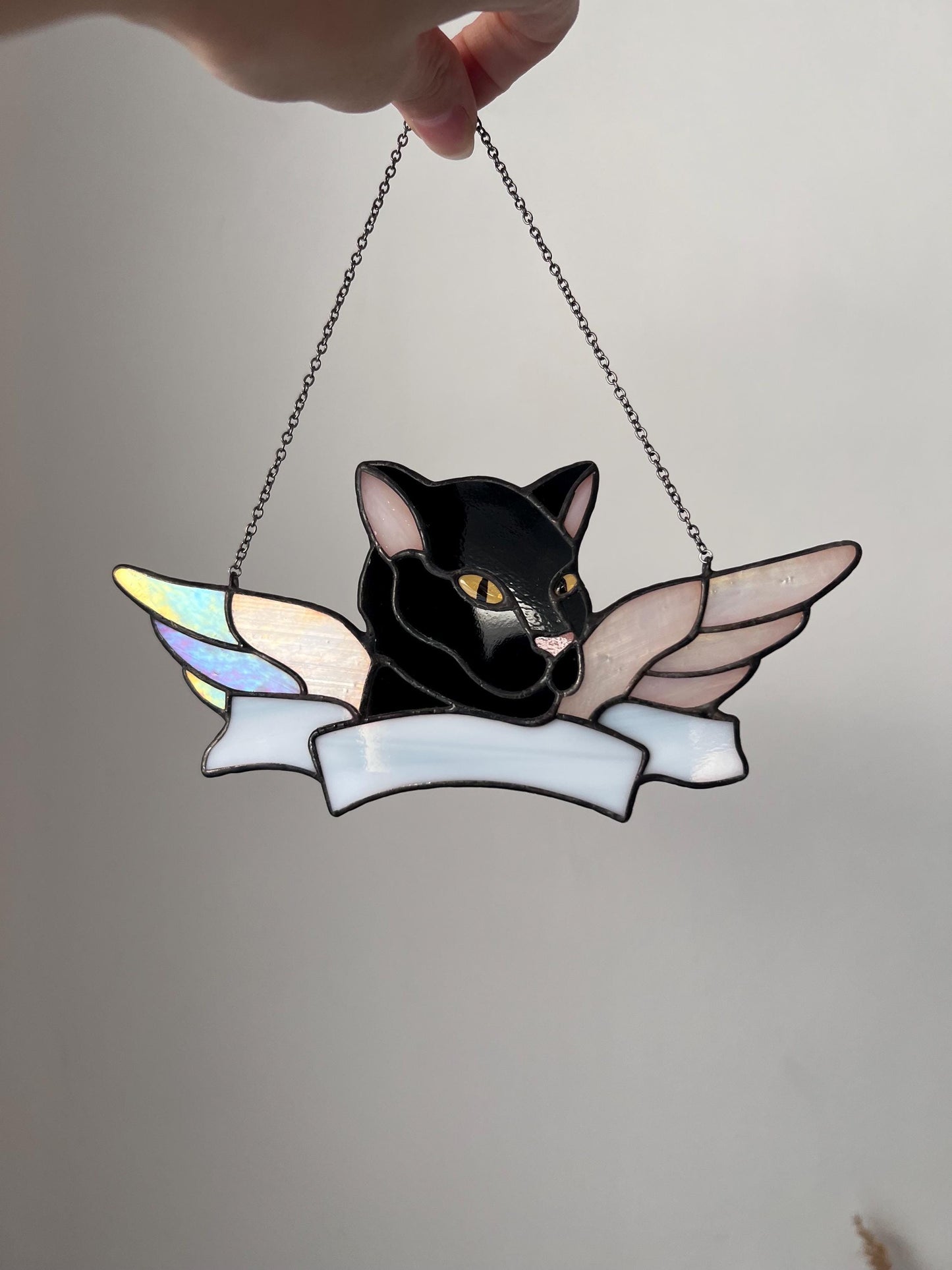 Stained glass cat suncatcher hanging in window with sunlight