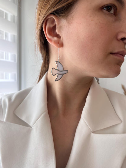 Handmade stained glass earrings shaped like white doves, photographed on model. Lightweight dangle bird earrings perfect for weddings, nature lovers, or meaningful gifts.