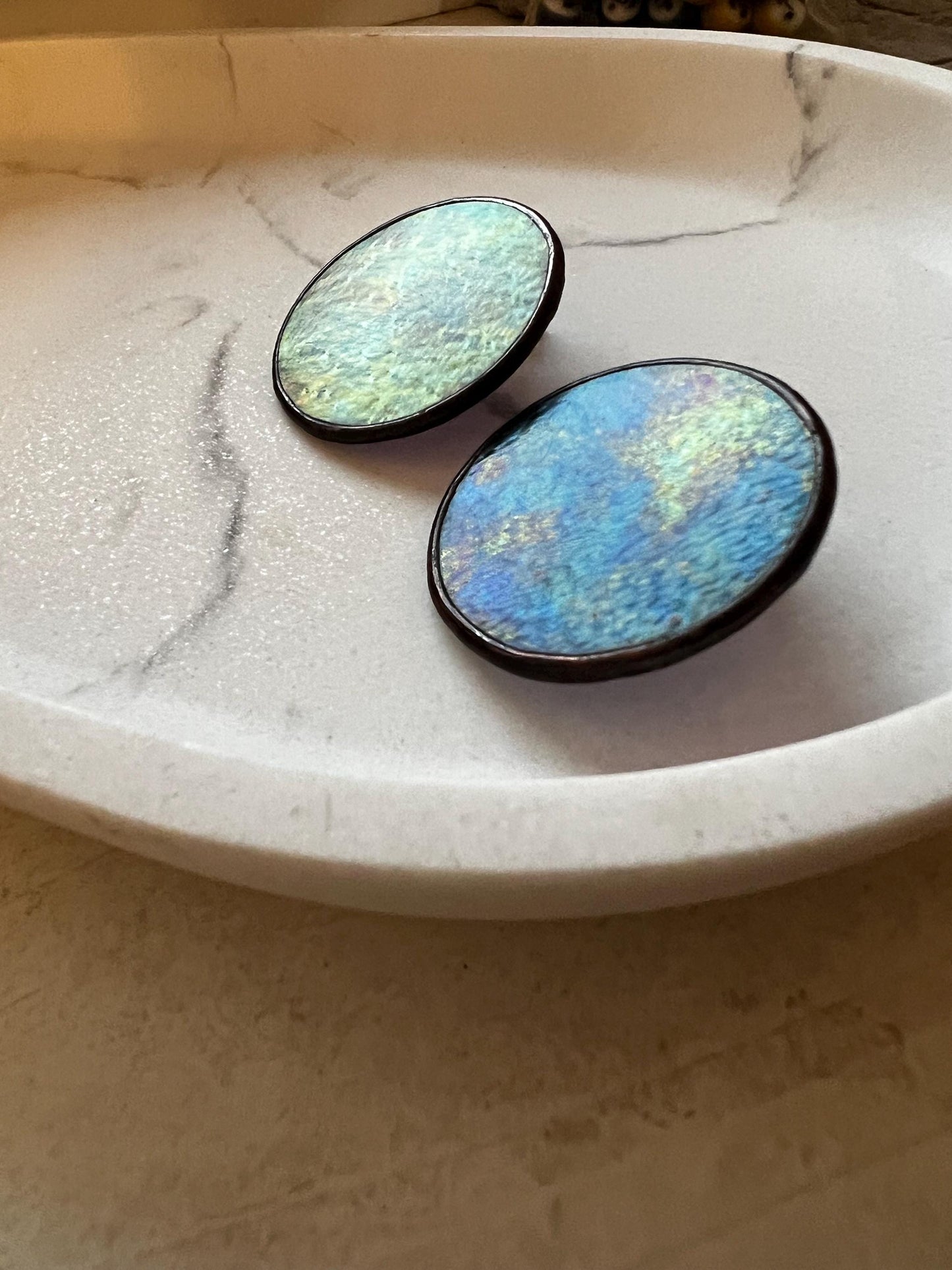 Iridescent black glass earrings on white decorate plate