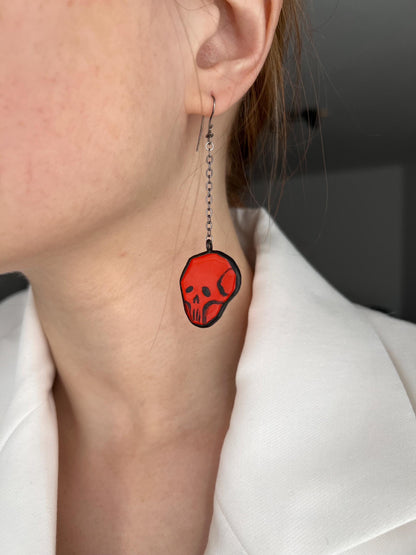 Close-up of red stained glass skull earring in ear