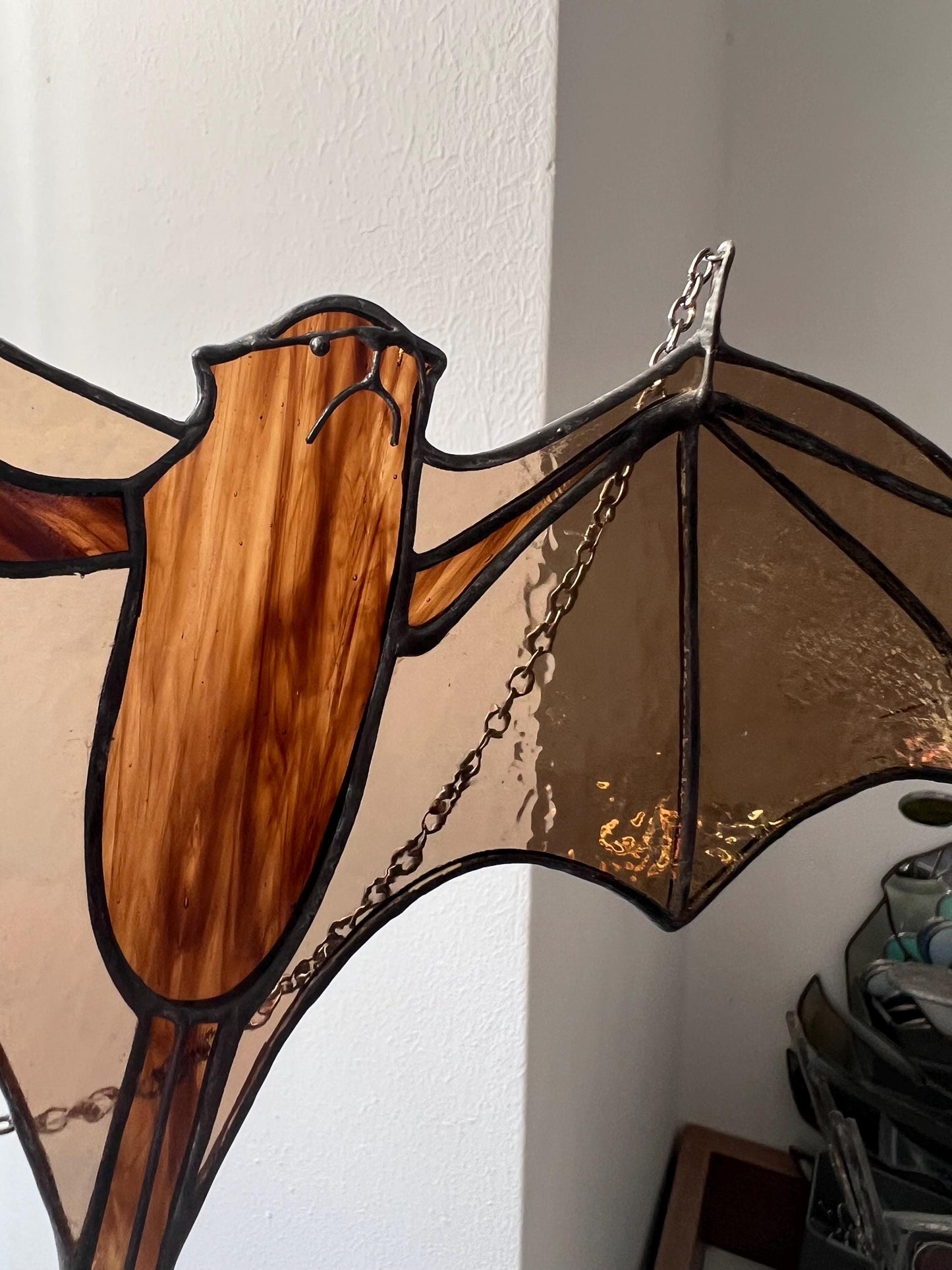 stained glass decoration in the form of a bat in amber and brown tones, the body is depicted in close-up, demonstrating the small details of the handwork and colors, which look even more interesting up close