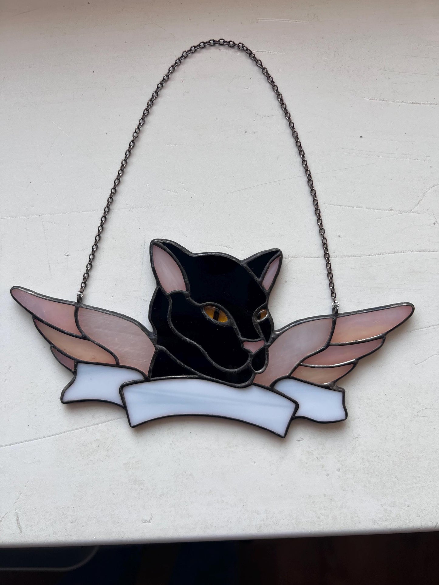Memorial stained glass cat decor displayed near window