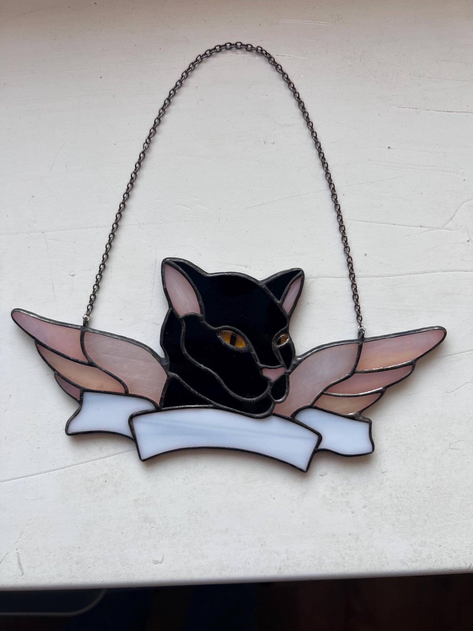 Memorial stained glass cat decor displayed near window