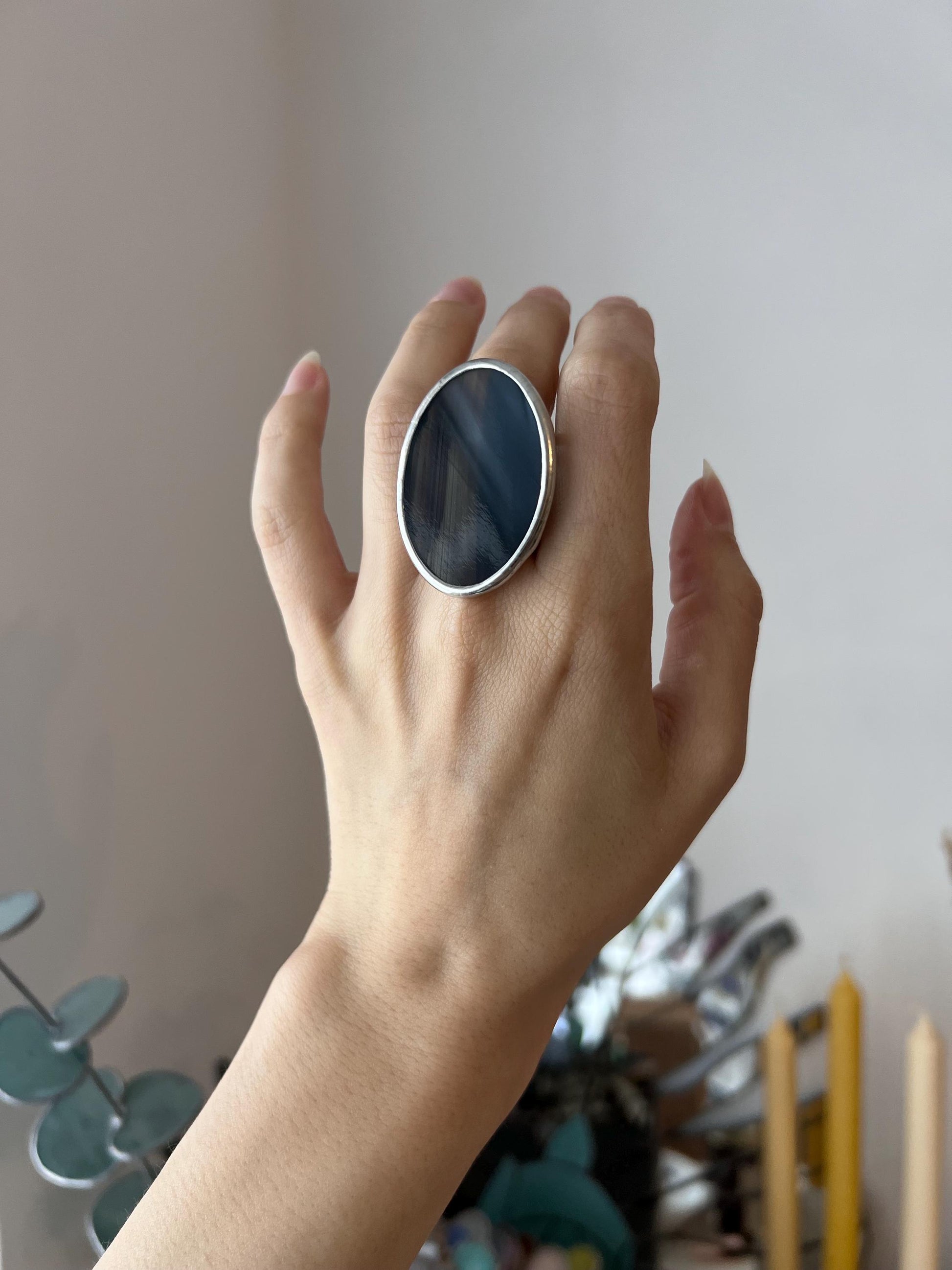 Massive black handmade ring with geometric design on interior background