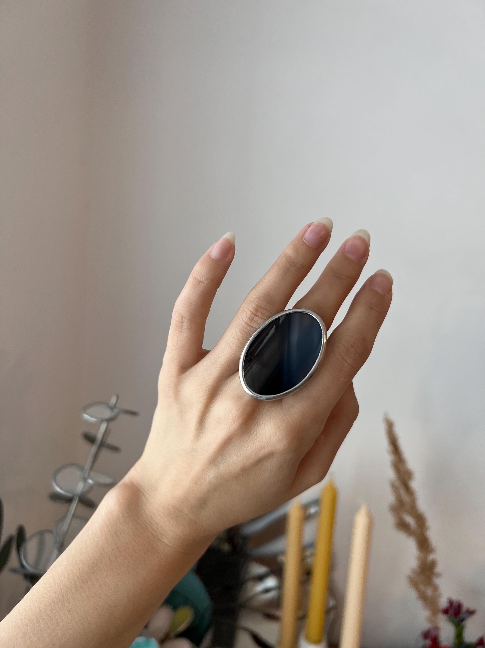 Large black oval ring on hand, close-up view, unique glass pattern visible