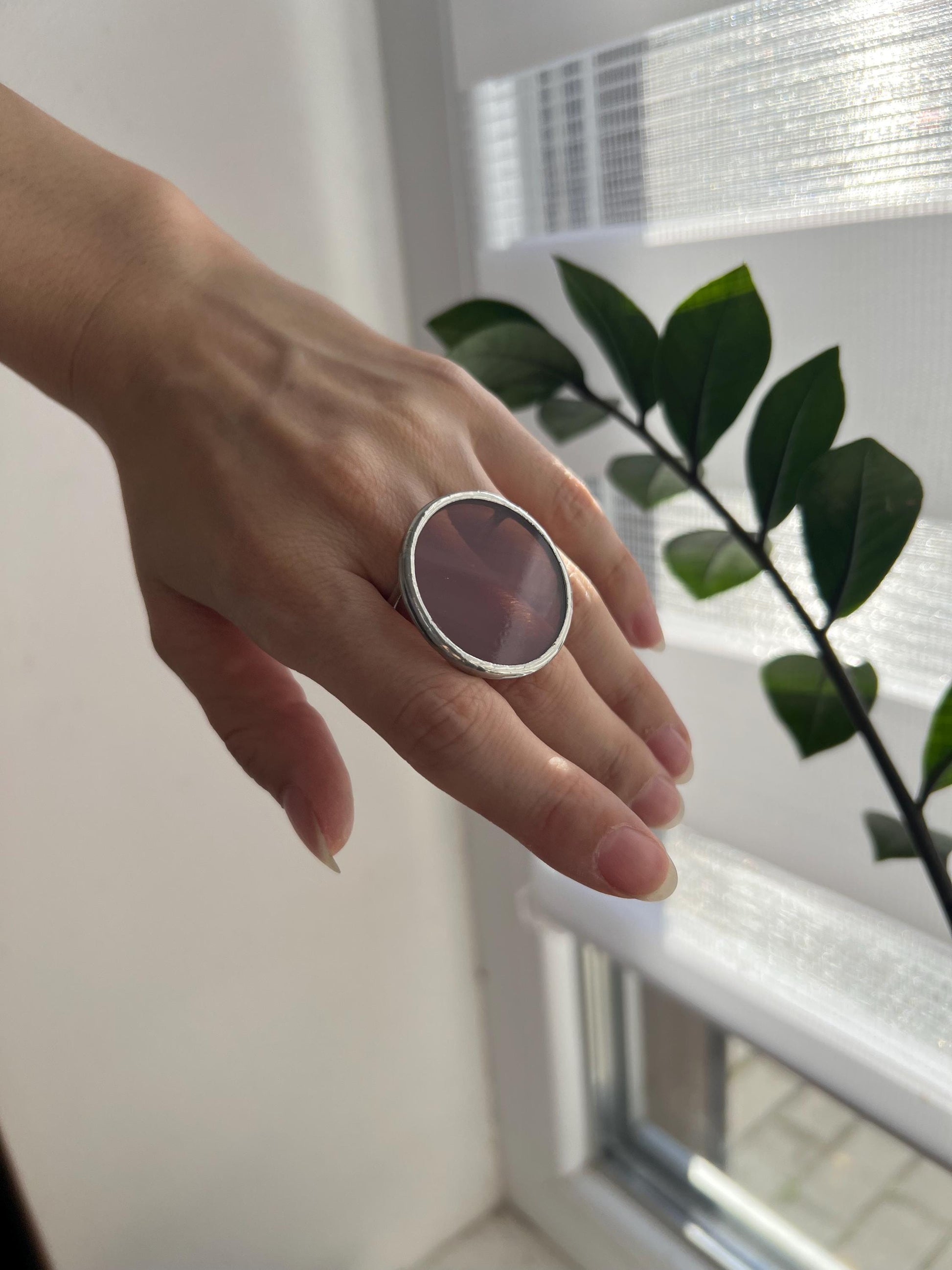 Hand with large plum stained glass ring – round statement disc