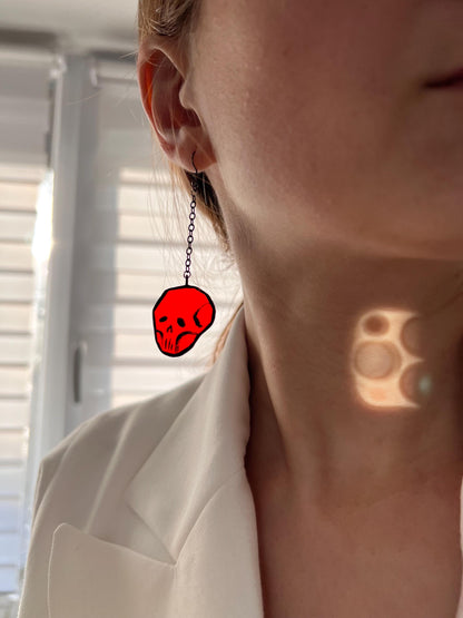Handmade skull earring catching the light, spooky shadows