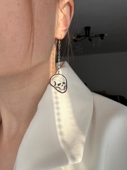 Close-up of transparent stained glass skull earring in ear
