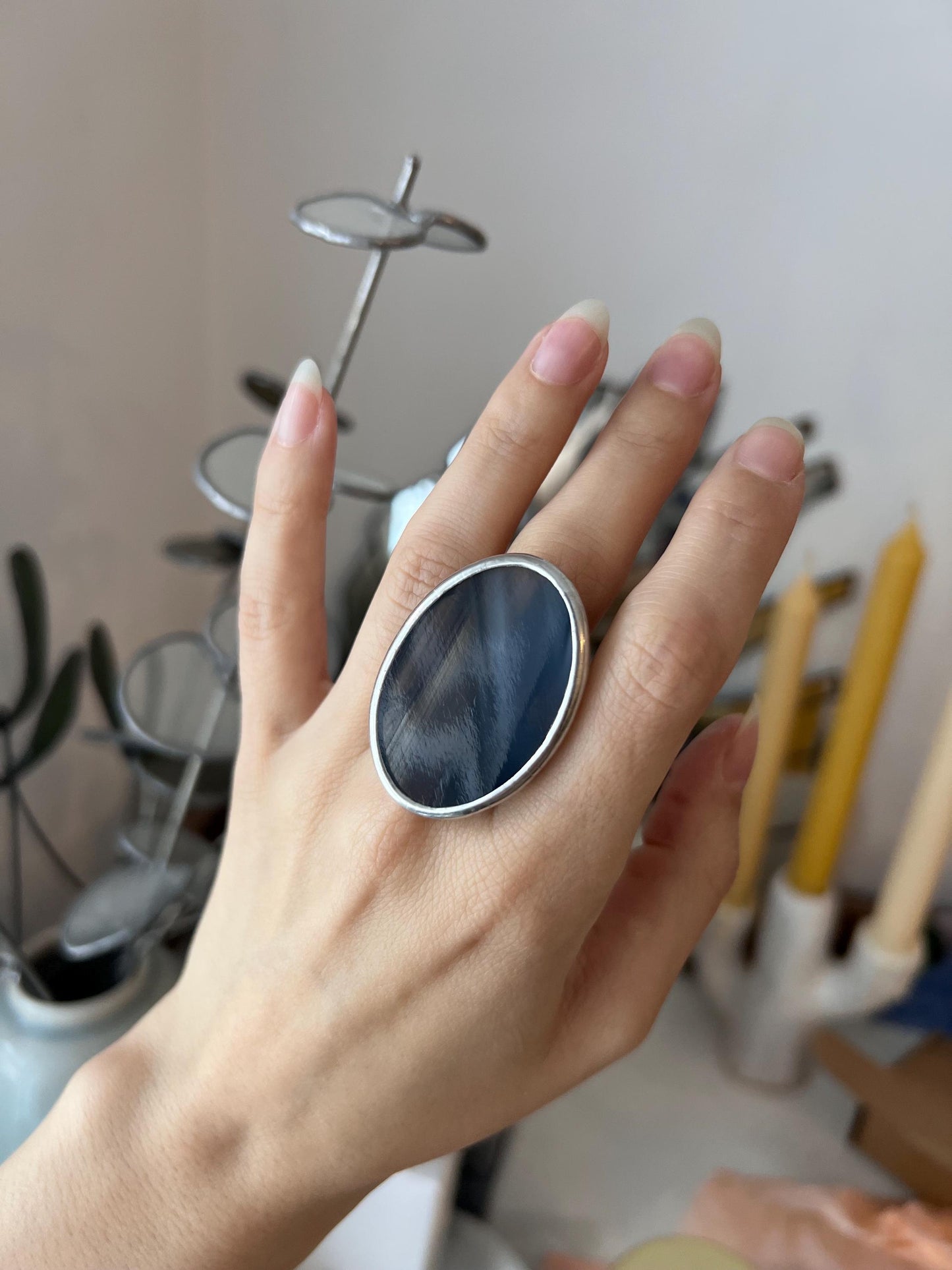 Large black oval ring with white streaks, made of stained glass, on hand
