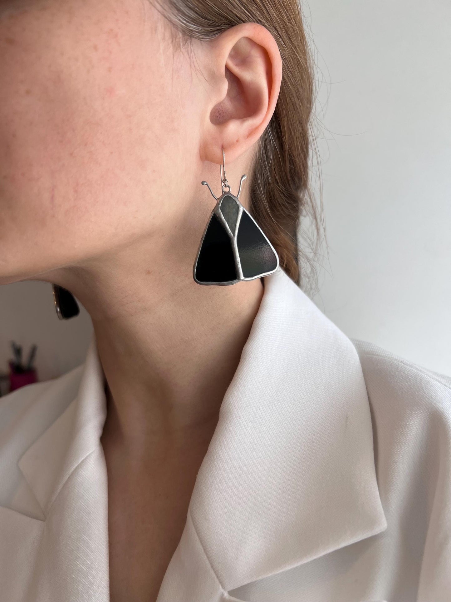 Woman wearing black butterfly stained glass earrings