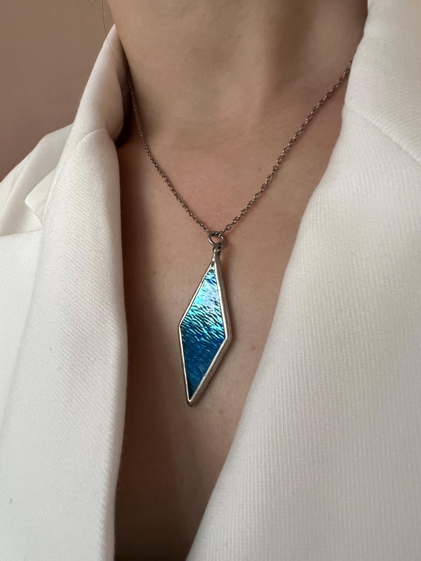 Close-up of a blue glass pendant with a metal frame, minimalist style.