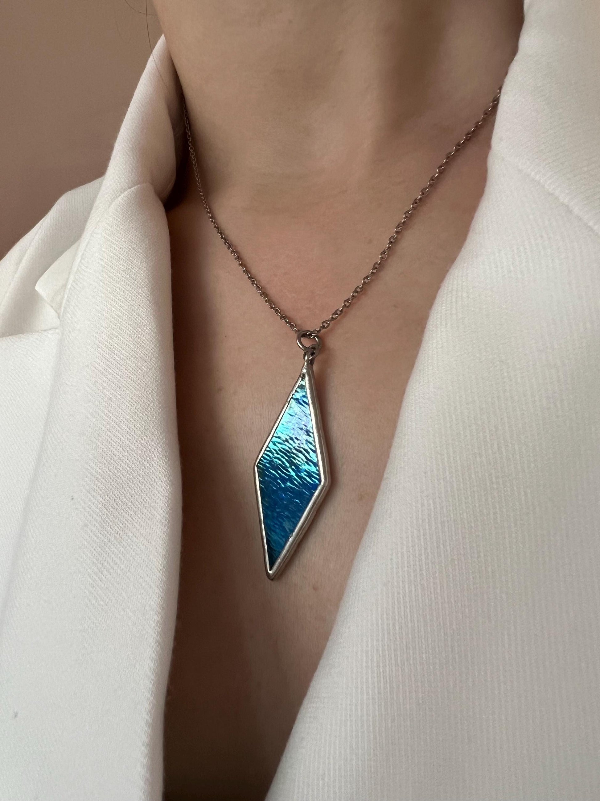 Close-up of a blue glass pendant with a metal frame, minimalist style.