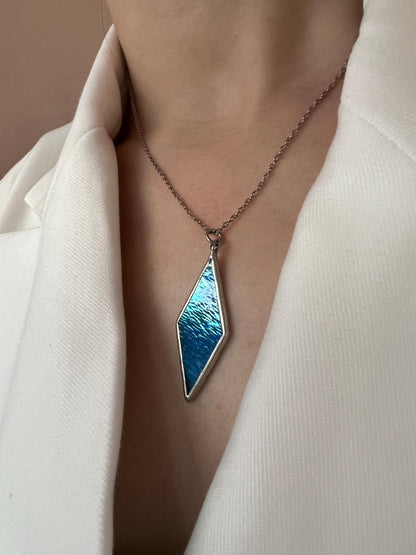 Close-up of a blue glass pendant with a metal frame, minimalist style.