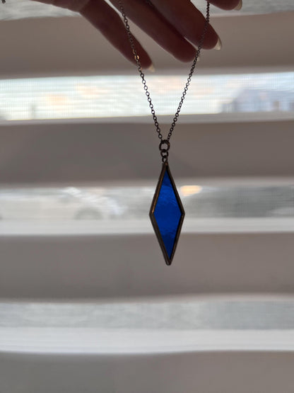 Blue glass pendant on a white background with a shadow - an emphasis on transparency and color.