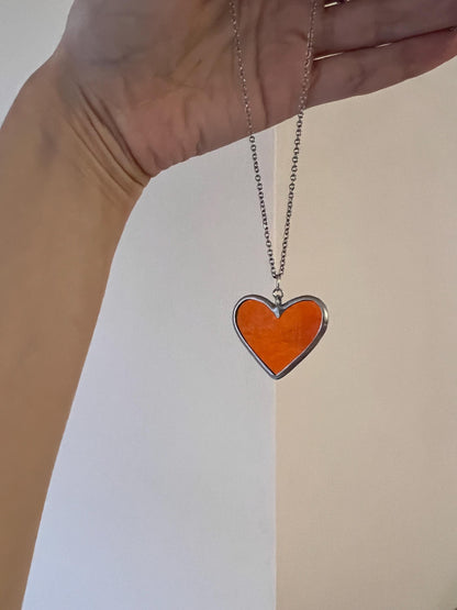 Heart pendant in hand, view of glass texture and shades.
