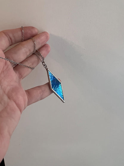 Handmade iridescent blue glass charm necklace in hand