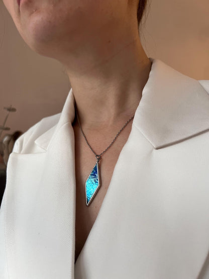 Unique geometric blue glass pendant on model’s neck