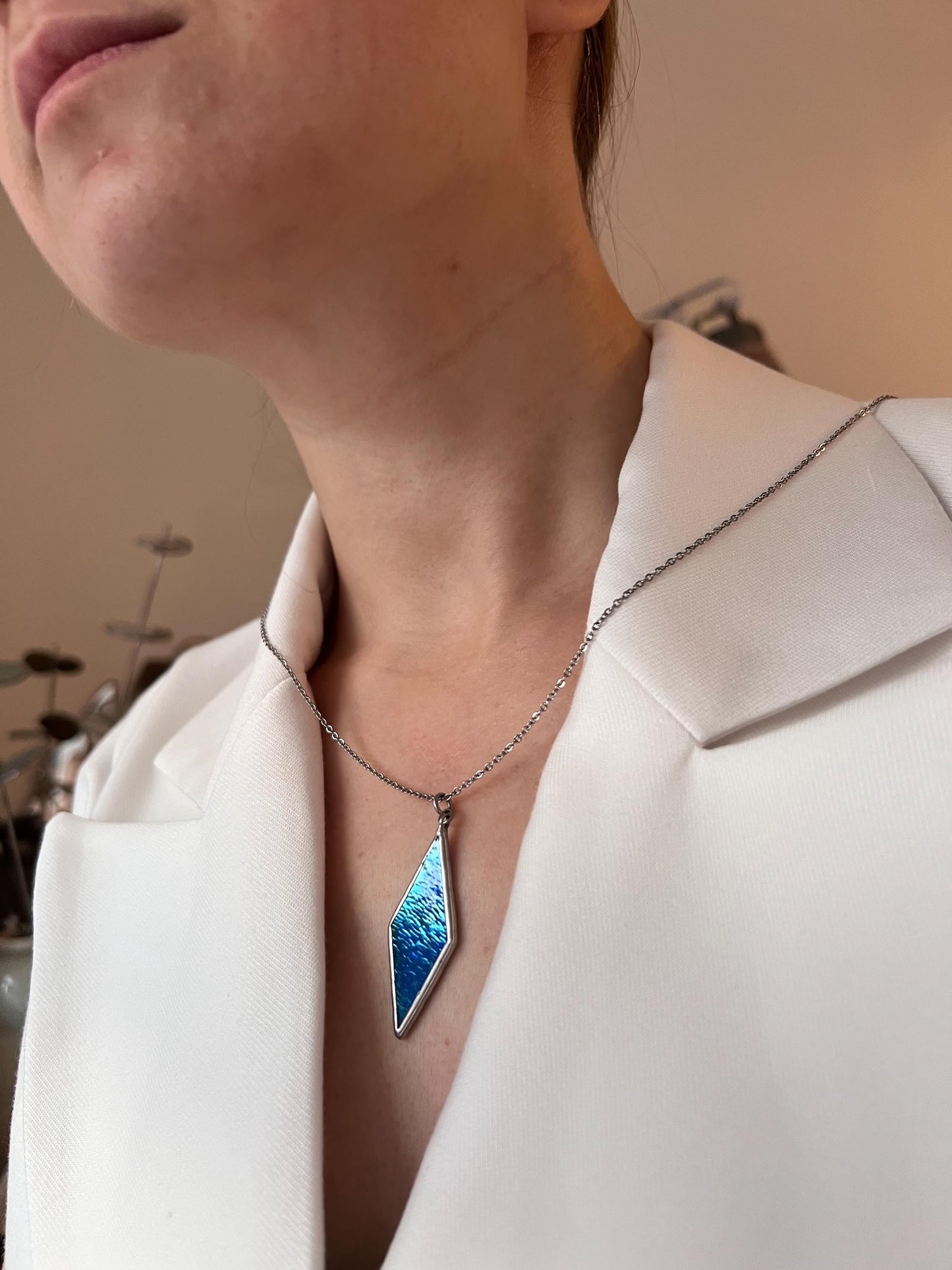 Modern blue glass necklace worn with white blazer