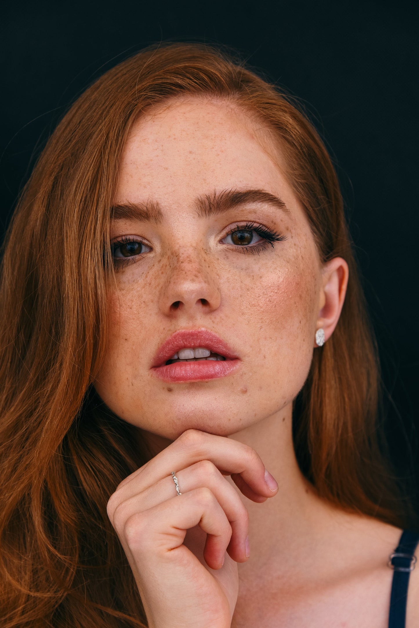 Model in a face frame, wearing a thin silver ring in a minimalist style.