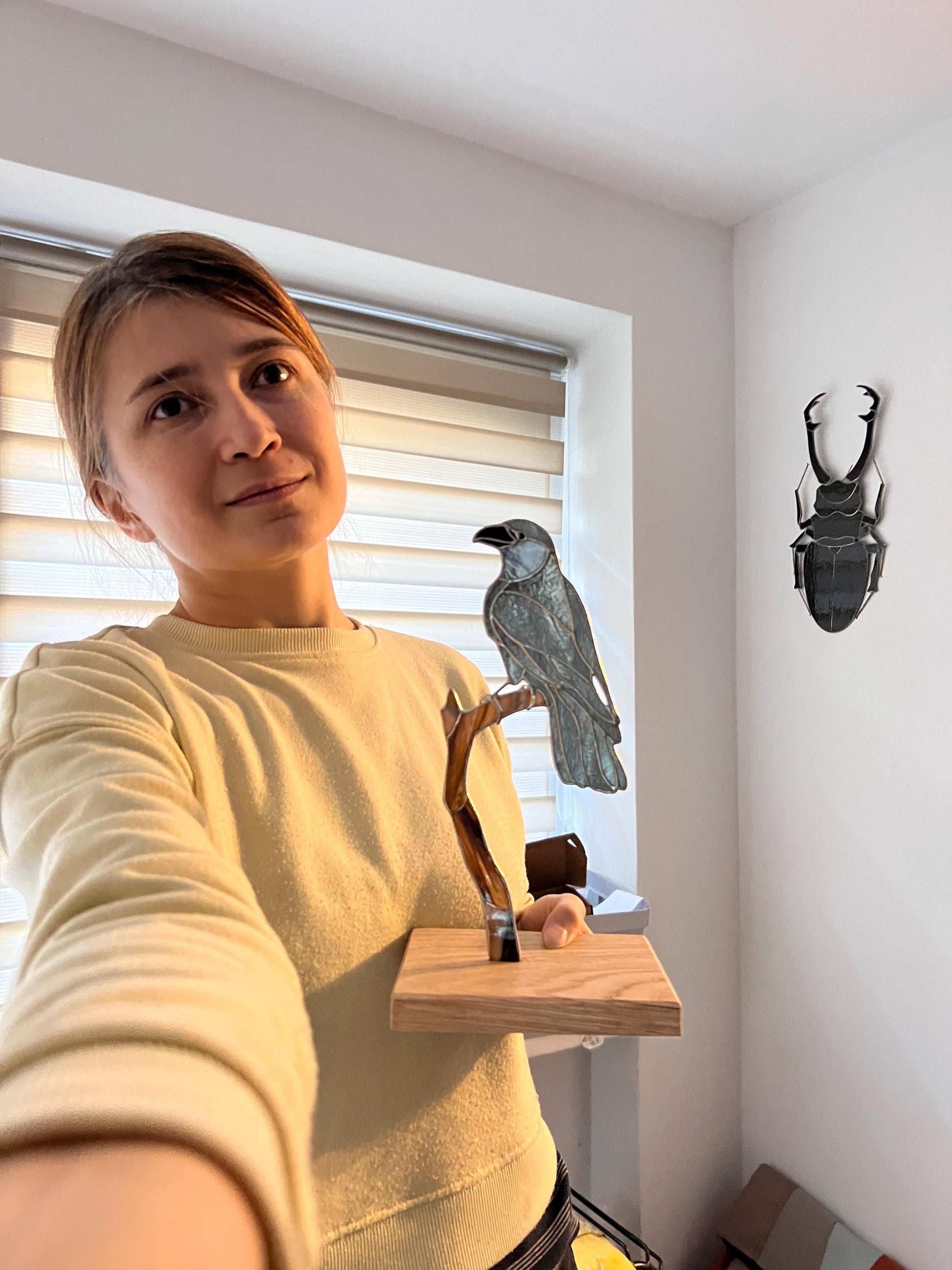 Artist holding handmade stained glass crow figurine – size reference photo