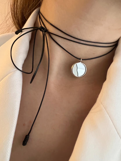 Assorted mirror cord necklaces on beige surface