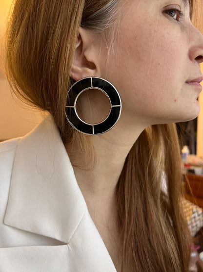 Close-up of glossy black stained glass circles on ear