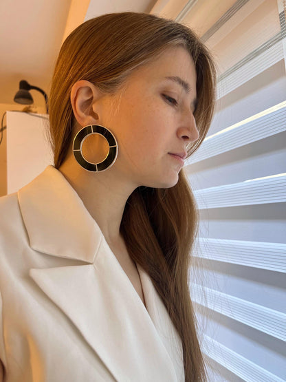 Woman wearing black stained glass hoop earrings, large geometric design
