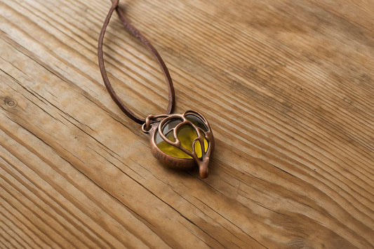 Yellow handmade glass pendant on wooden background