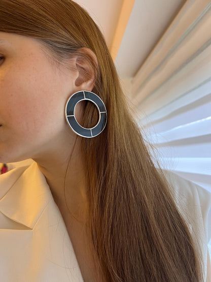 Model in white blazer wearing large black hoop statement earrings