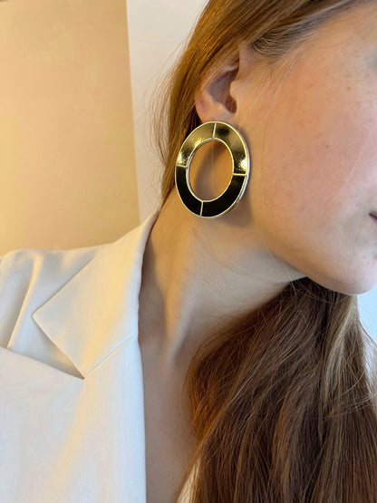 Model in white jacket wearing bold black circle earrings