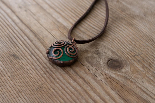 Green handmade glass pendant on wooden surface