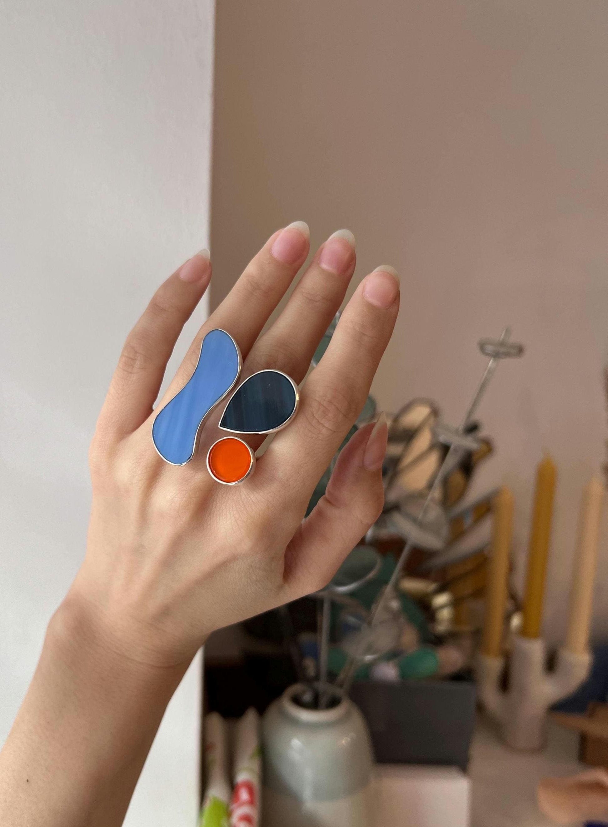 Sculptural handmade silver ring with blue, orange, and black glass, modern artisan jewelry with organic form.
