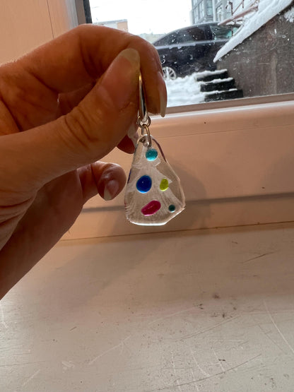 Fused glass Christmas tree earrings held in natural daylight