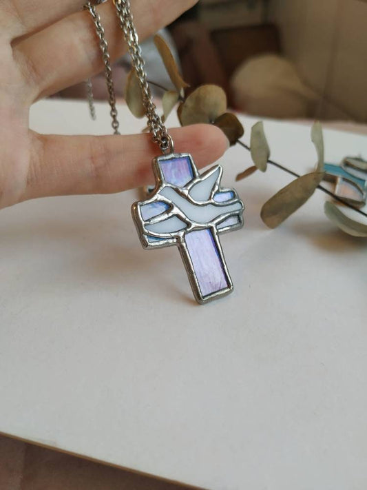 Close-up of Purple-toned cross pendant with bird detail in hand